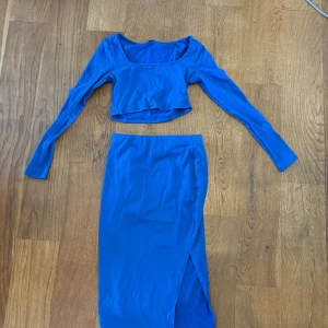 Blå tvådelad klänning - En blå tvådelad klänning med långärmad topp och en långkjol med slits. Toppen och kjolen är ribbad.