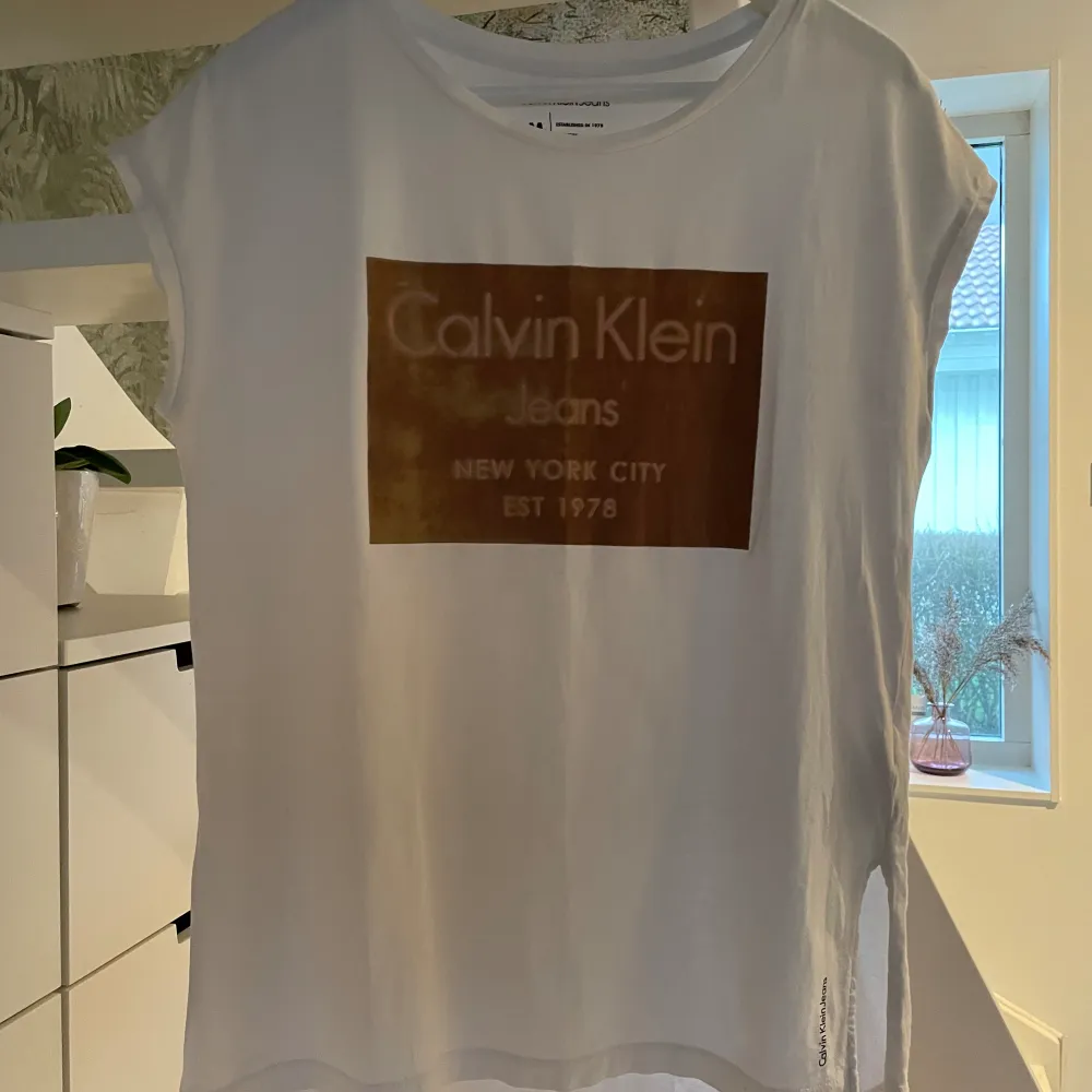 Fin och användbar T-shirt eller topp från Calvin Klein i vitt. Original, dyr i inköp men säljes för 100 kr, så bra pris.  Fint skick, inga fläckar eller hål. Rymlig i storleken. Stl M . T-shirts.