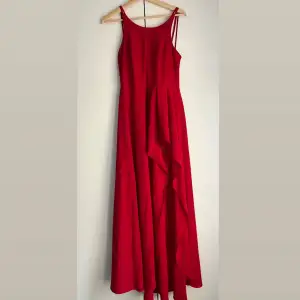 En röd balklänning (maxi) med snitt. Som ni kan se på andra bilden har klänningen en fin detalj med spets på bensnittet.