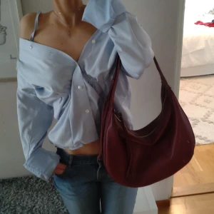 Vinröd läder väska  - Supersnygg vinröd läder bag i fint skick med guldspänne som går att justera och dragkedja på både ut och insidan!❤️✨ Köp gärna direkt!⭐ Nypris: 399 kr