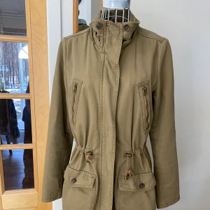 Vårjacka  - Superfin jacka med snöre som man kan dra åt i midjan, flera fickor och längre modell