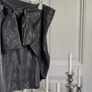 Supersnygg silver/svart metallic kjol som knyts snett framtill för lite edge. Ascool, och i nyskick. 🩶