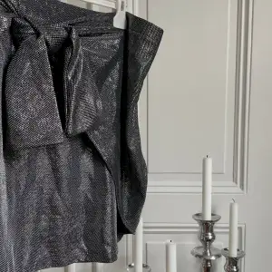 Supersnygg silver/svart metallic kjol som knyts snett framtill för lite edge. Ascool, och i nyskick. 🩶