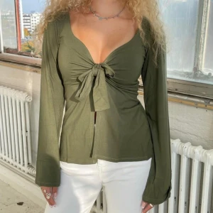 Blus - Blus i mjukt och stretchigt material, passar de flesta storlekar. Normal passform och långa ärmar som vidgar ut i ändarna. V-ringning och knyts med ett band fram, kan även knytas som på sista bilden. Material: 95% viskos och 5% elastisk
