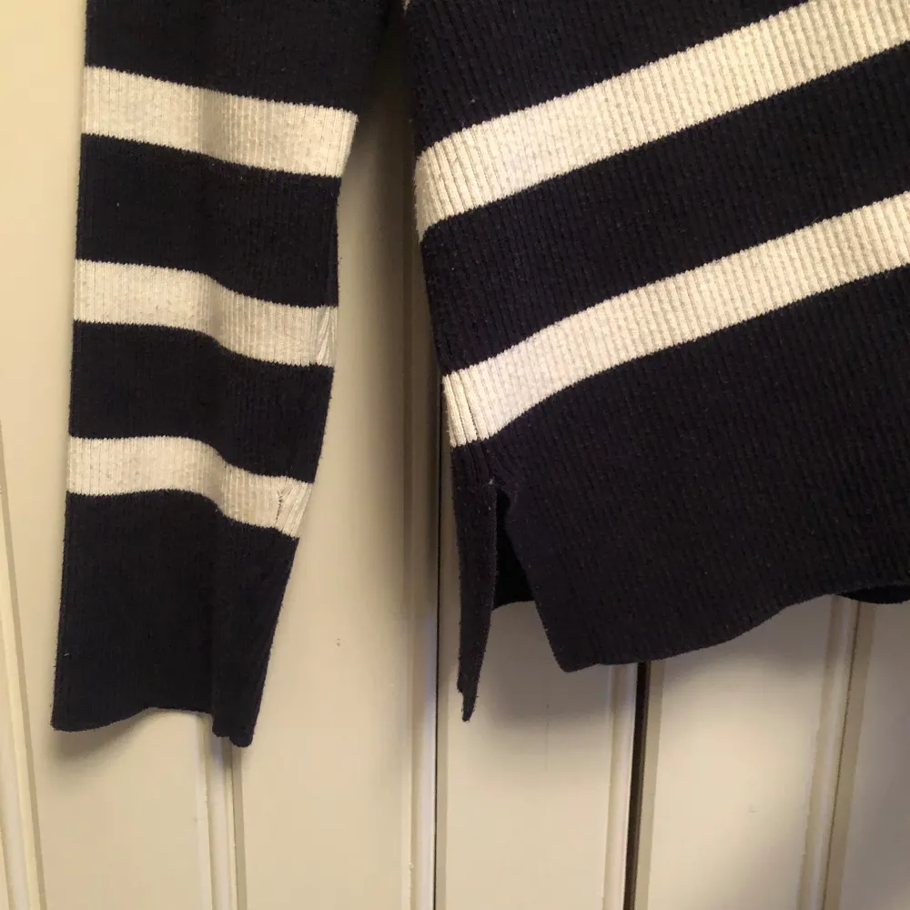 En mörkblå stickad tröja med vita ränder och små slitsar längst ner 🤍 Använd några gånger men inga defekter!. Tröjor & Koftor.