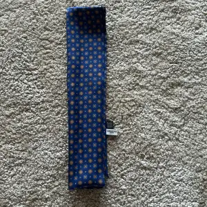 Silkesscarf från John Henric i en snyggt mönster med blå som basfärg! 100% Silke och använd en gång, dvs i nyskick!