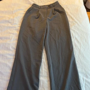 NA-KD kostymbyxor  - Superfina gråa kostymbyxor från NA-KD i storlek 34. Säljes på grund av för små för mig, väldigt bra skick, knappt använda! Vida ben, normal midja.