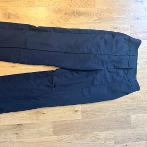 Lågmidjad kostymbyxa NA-KD - Super snygg och SÅ sköna, lågmidjade kostymbyxor från NA-KD. De är i strl 34 men är tyvärr för stora i midjan för mig så därför säljer jag dem nu. De har även en slits på var sida i nederkant som faller väldigt fint över skorna.