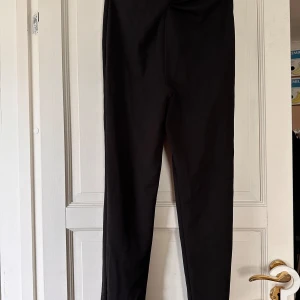Svarta byxor - Svarta ”fin” byxor från Nelly trend . Höga i midjan med en snurrdetalj. Stretchigt material 