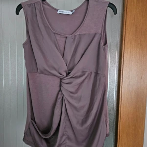 Lila ärmlös topp från See by Chloé - En elegant lila ärmlös topp från See by Chloé. Toppen har en unik knutdetalj framtill som ger en draperad effekt. Den är tillverkad i ett mjukt och bekvämt material, perfekt för både vardag och fest.