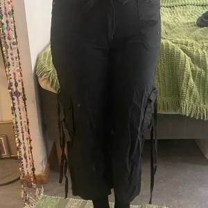 Svarta cargopants - Snygga svarta lowaisted cargopants som tyvärr är för små för mig! Snören man kan låta hänga eller knyta om man vill. Köpta second hand men inte använda av mig. Vet inte exakt storlek men skulle säga typ S. 