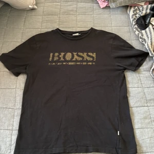 Hugo boss t shirt - Säljer min snygga Hugo boss t-shirt i färgen svart och guld därför den är för liten. Tröjan är i ett bra skicka 8/10 och är i storlek S. Väldigt bra pris;)