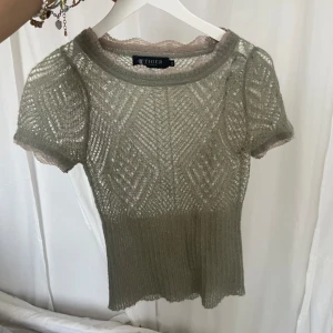 Grön stickad topp från Tiger - grön stickad topp från Tiger med korta ärmar och ett vackert mönster. Toppen har en rund halsringning och är något genomskinlig. fest topp snygg 