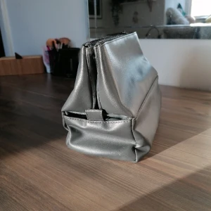 Stor neccessär  - En stor grå neccessär med tre fack där dem två yterfacken kan knäppas ihop så att man kan ta med den. Skriv om intresse eller frågor. 