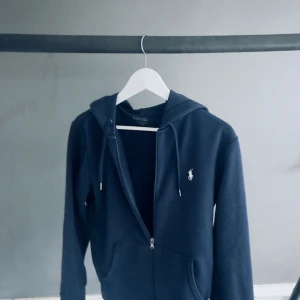 Ralph lauren zip hoodie storlek s - Ralph Laurent zip hoodie Lite trasig vid fickorna men annars bra marinblå färg köpt på Nk i Stockholm tyvärr finns inte kvitto kvar. Storlek s.         170 i längd