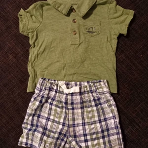 Set shorts piké strl. 6 mån - Set med grön pikétröja och rutiga shorts i storlek 6 mån (ca strl. 68) från Carter's. I fint begagnat skick, inga hål eller fläckar.   Tvättade i parfymfritt tvättmedel och utan sköljmedel. 