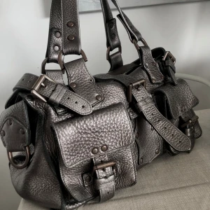 Mulberry Roxanne Gunmetal metallic  - Vintage väska i klassisk modell i en färg som är svår att få tag på. Silver/Brons - heter Gunmetal.  Väskan är ca 25 år gammal köptes i början av 2000 talet. Finns lite slitage men bra skick. Lädret är jätte fint, mjukt men kraftigt. 