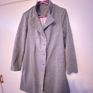 Kappa - Grå kappa, helt oanvänd. Strl S. Längden är ner till knäna och fin i ärmarna. Super fina knappar och fint material. Nypris 400kr