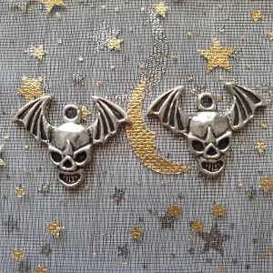 2st dödskalle vingar berlock, hängsmycke, smycke  - Berlocker, hängsmycke  Motiv: dödskalle huvud med vingar  Färg: silverfärgad  Antal:  Skick: 2st Går tex att sätta dem på halsband, armband eller göra örhängen av dem.  Till annat pyssel eller utsmyckning 
