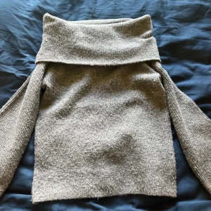 Stickad tröja  - En grå stickad tröja från H&M. Man kan vika ner axlarna.