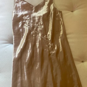Silkes klänning - Gullig silkesklänning med openleg på sidan.  Har fler bilder så det är bara att fråga! 😊 blommor broderade på framsidan. Helt oanvänd!🎀 Bra kvalite!  Skriv om du vill ha mått på specifika delar av klänningen. Klänningen är köpt vintage. 