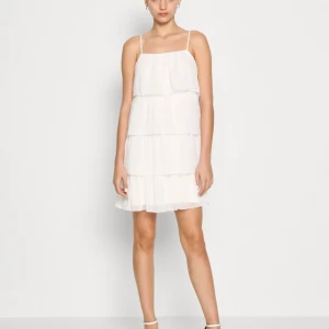 Klänning - Jättefin vit klänning med volanger perfekt för student eller skolavslutning. Den är bara använd en gång och jag säljer då jag inte kommer använda den igen. Köpt för 400. Passar M/L! Skriv för fler frågor💗💗