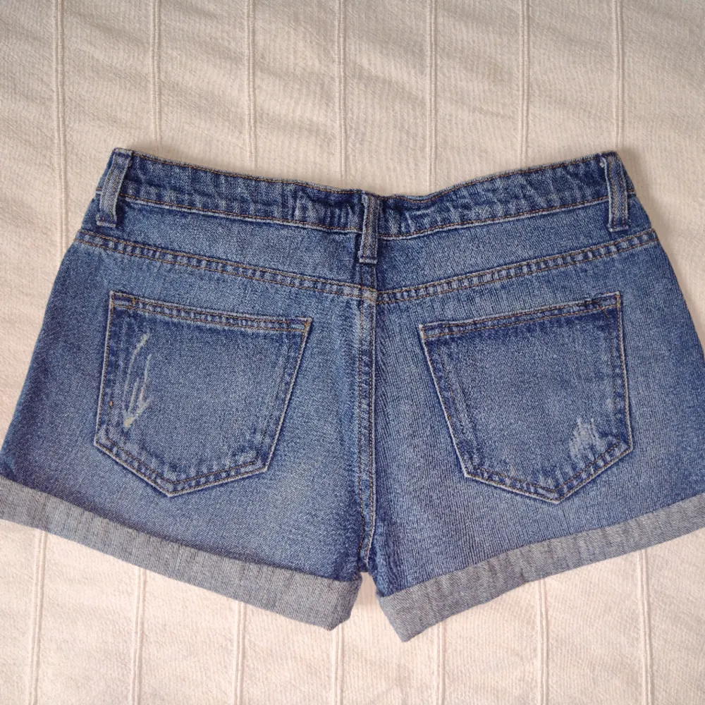 Blå korta jeansshorts från Cubus i 100% bomull. Sparsamt använda och i fint skick. Snygga slitna detaljer och låg midja. Storlek 36.. Shorts.