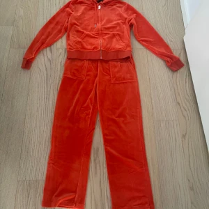 Juicy Couture mjukisset  - Nyskick. Använt en gång. Storlek M.  Byxorna har jag fått korta ner. Innerbenlängd är 70cm nu. Färgen är mörk orange.