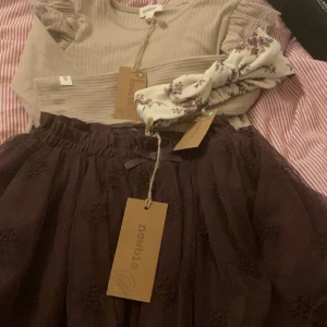 Newbie outfit  - Säljer dessa plagg från Newbie helt nytt bara testat.Både kjolen och tröjan är i storlek 98/104 och hårbandet är i one size.Kjolen köpt för 299kr,tröjan 179kr och hårbandet för 79kr. 