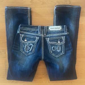 low waist bootcut jeans från rock revival. midjemått 37/38 cm, innerbenslängd 83 cm. diamanter har trillat av på vissa ställen, annars bra skick. skriv om du har frågor eller vill ha fler bilder! priset kan eventuellt diskuteras 😊