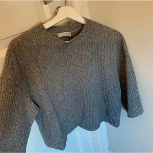 Grå Stickad t-shirt - Säljer en sån här populär stickad t-shirt från märket mango. Den är ribbstickad och är en trekvarts / t-shirt modell som är skitsnygg på 😍 säljer då den inte kommer till användning så mycket! Storlek S men passar XS/S! Skriv priv vid frågor 🩷