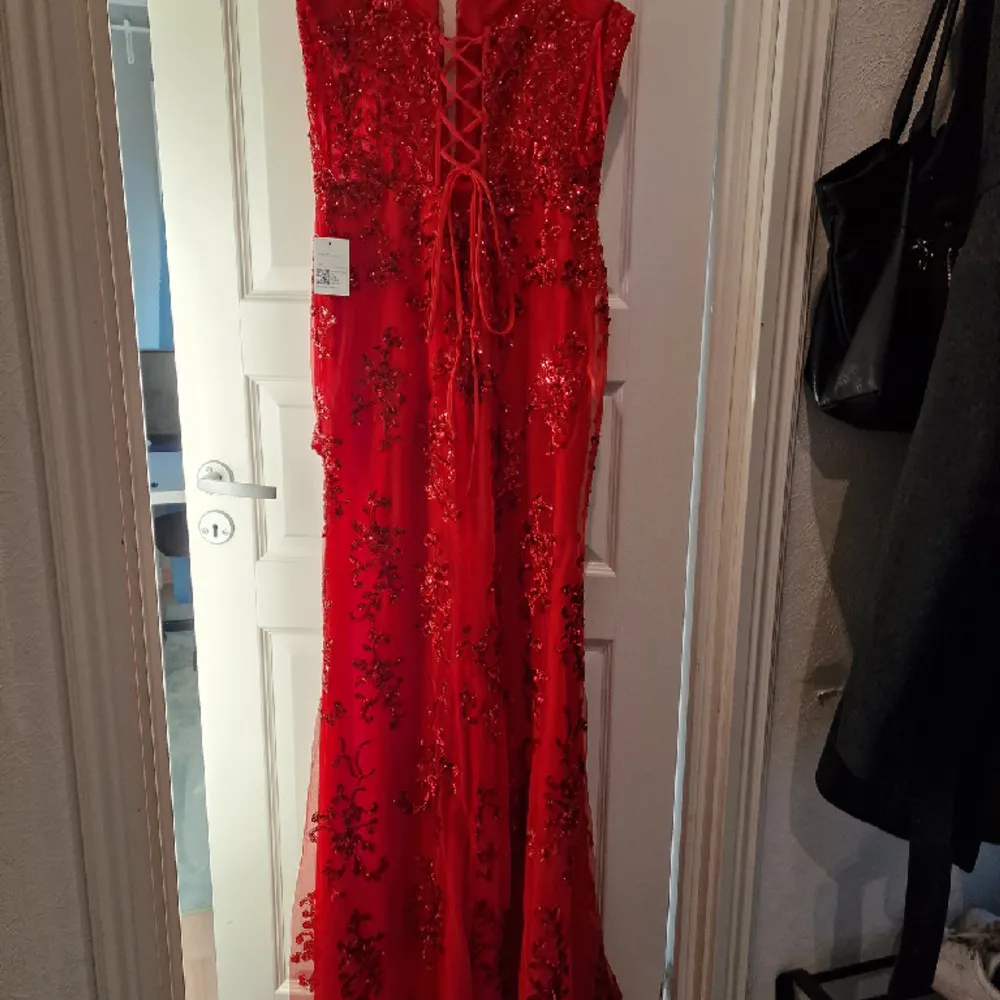Säljer denna fina röda balklänning då den är lite för liten och har hittat en annan.   Aldrig använd bara testad.   Paljetter i mönster på hela klänningen, storlek 42 men snörning i ryggen så den går att justera lite.. Klänningar.