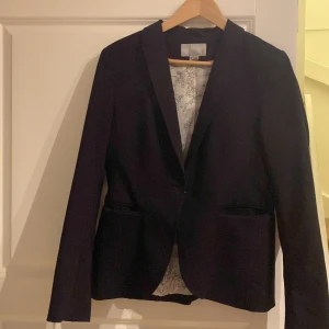 Svart kavaj HM - Säljer en svart kavaj från H&M, stl 40. Mönstrad insida. En knapp framtill. Knappar vid ärmslut.   