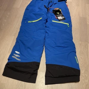 Isbjörn skidbyxor 122/128 - Isbjörn skidbyxor storlek 122/128. Aldrig använda, originaletiketter sitter kvar. OBS! Inga hängslen. Vattenpelare 15000 mm. Säljes på grund av felköp.