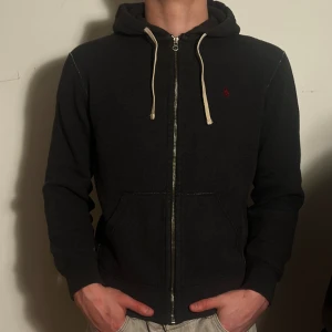 Grå Polo Ralph Lauren Zip Hoodie - En Grå Polo Ralph Lauren Fullzip Hoodie i Välomhändetaget skick! Några förglossnade områden. Storlek M men passar även bra som S. Modellen är 182 cm och väger 75 kg Pris öppet till förhandling!