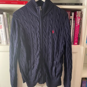 Polo Ralph Lauren - Stickad Fullzip Tröja - Knappt använd tröja som har hög efterfråga. Inga defekter. Skick är 9/10. Storlek S fast passar mer som M. Krage kan vikas utåt. Ordinarie pris är ca. 2000kr💰