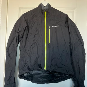 Svart Everest Jacka - Enkel och klassisk svart Everest vind och regn-jacka med neongröna detaljer. Bra använt skick. Ficka innanför jackan som har öppnats upp, går säkert att stänga ihop igen (bild 3). Storlek 36, normal i storleken. Upphämtning i Malmö möjligt. 