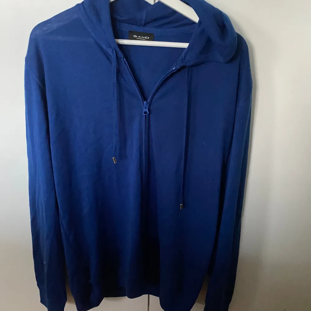 Säljer denna blåa zip hoodie från sand. Den är i bra skick och har skönt material. Den är i storlek l men sitter mer som M. Hoodies.