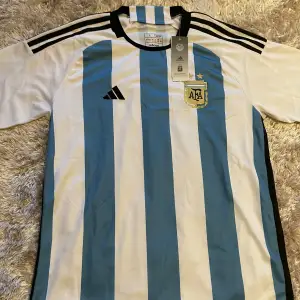 Säljer nu denna supersnygga Argentina tröja från VM 2022🔥 Tröjan är helt oanvänd och lappen är kvar! Nyskick!! Perfekt nu till sommaren och passar både storlek L och M. Skriv privat vid frågor!🤗