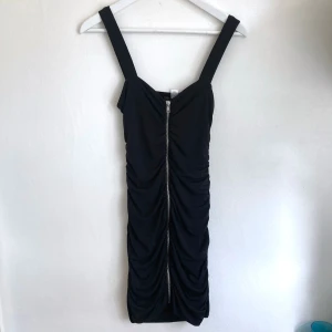 Svart tight miniklänning, stl 34 XS, figurnära, dragkedja, goth, punk, fest, party - Svart figurnära miniklänning från H&M Divided. Elastiskt rynkat material, silverfärgad dragkedja. Mått i cm: bröstvidd 34; längd fram från axeln 79.
