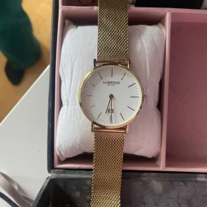 Lorenzo Milano klocka  - Boett täckt av 18 K guld Klockans boett är täckt av 18 karat guld. Både tidsindexering och visare är även de täckta av 18 karat guld. Köpt för 1695kr. 