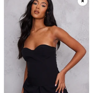 Svart bandeau top - Säljer denna svarta bandeau top från ”PrettyLittleThing” som är lite strukterad likt en korsett. Aldrig använd bara testad. Skriv privat om ni har några frågor🩷