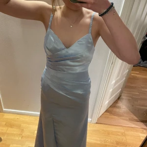 Balklänning  - Säljer denna jätte jätte fina ljusblåa balklänningen med assnygg rygg!!❤️❤️  Jag är runt 177 cm lång och väger ungefär 60kg🥰  Den har slits vid ena benet och paljett detaljer vid ärmarna och ryggen! Det Finns även en liten påse med extrapaljetter!