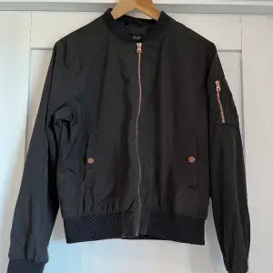 The black label collection bomber jacket med roséguld detaljer, dragkedja på vänster arm. 