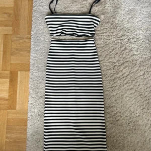 Top och midikjol från Zara - Snygg randig tvådelad set med en crop top och en kjol. Toppen har tunna axelband och kjolen har en slits bak.  Endast använt en gång, i mycket gott skick.  Stolek: kjol: S, topp: M