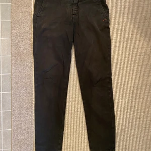 Dondup chinos  - Säljer ett par svarta dondup chinos i smal passmodell, storlek 164. Säljes i befintligt skick. Har lite förslitningsskador (en liten sömn vid ena fickan, går att fixa själv, därav priset. Köptes på W19 i Göteborg för ca 2100 kr. Skriv vid fundering. 