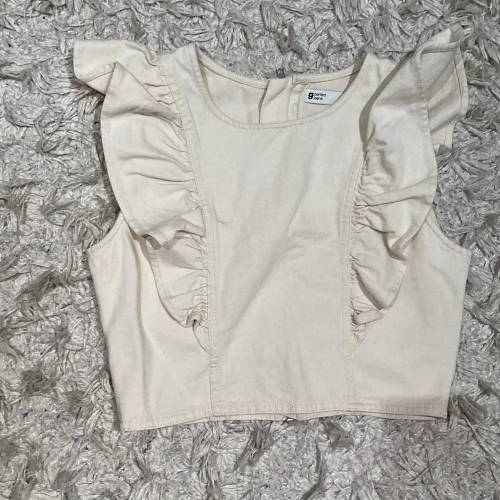 Beige/krämvit topp i mjukt jeanstyg. Köpt på Gina för några år sen. Oanvänd så inprincip nyskick!! Går att ha både framsidan och baksidan- som ”kofta” med tröja under eller som en topp. Skriv för fler blidee. Toppar.