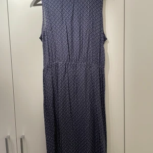 Sommarklänning  - Knälång tunn sommarklänning med resår i midjan och knäppning baktill, fina klädda knappar. 