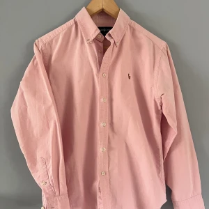 Ralph Lauren - Säljer en fet Ralph Lauren skjorta i färgen ljus rosé. Den är i storlek S men sitter som XS. Uppskattad längd för bra passform skulle vara 168-172. Skick 9/10 Tveka inte på att höra av dig!