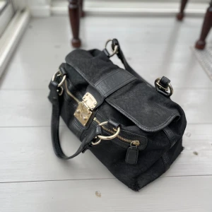 DKNY väska - Äkta DKNY väska med dust bag.  I använt men gott skick, lite slitage i underkanten (se sista bilden) samt på spännet. Praktisk väska som får plats med mycket och med många små fack.